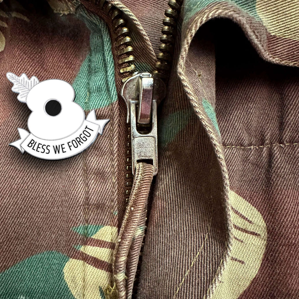 Camouflage jacket with a zipper and 'Bless We Forgot' poppy pin.