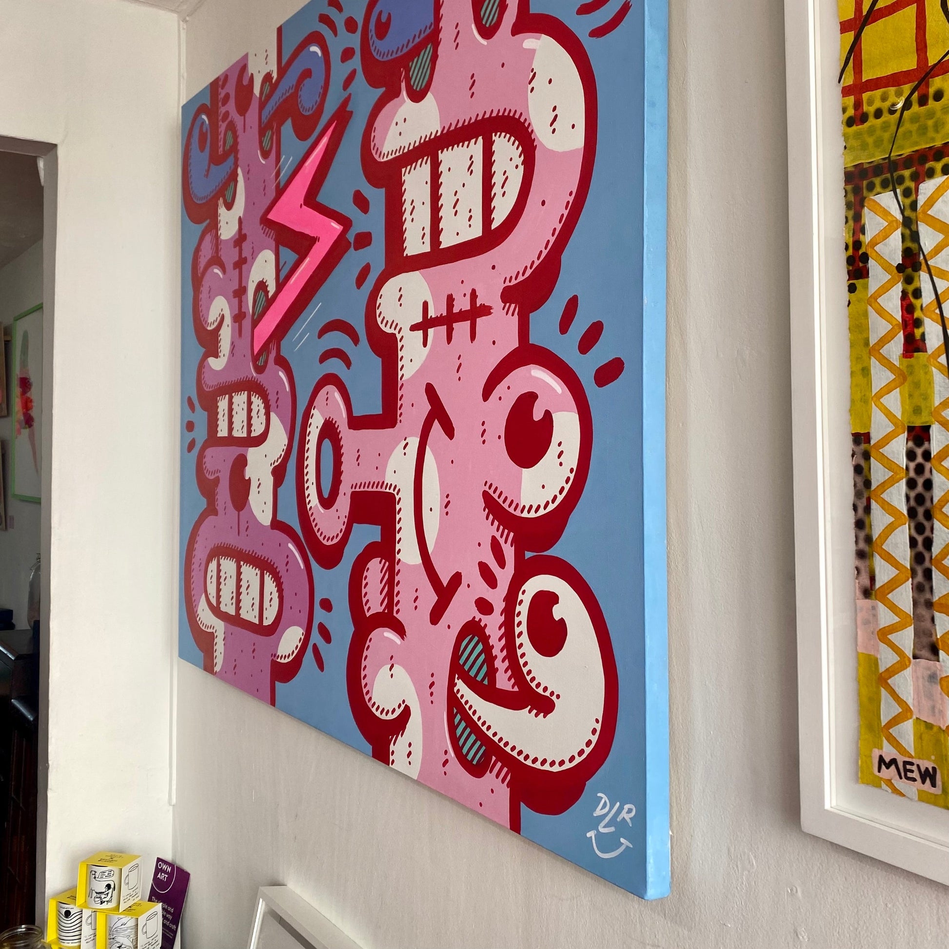 Colorful abstract artwork on a wall with a signature at the bottom right corner.