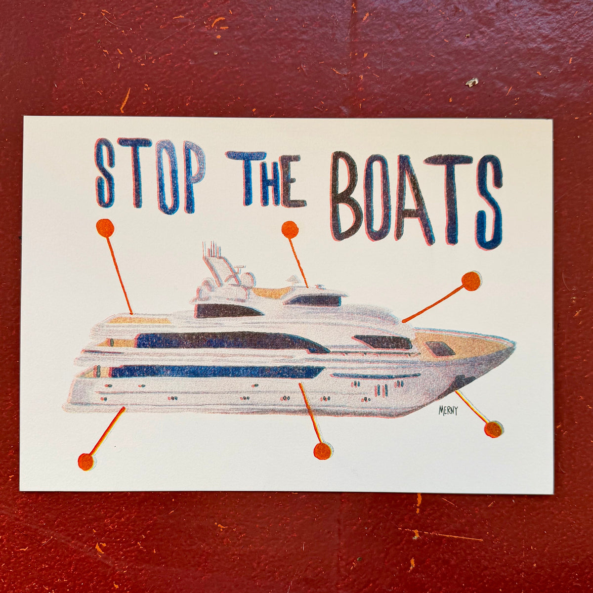 A square art print with the text 'STOP THE BOATS' above a hand-drawn illustration of a yacht, with orange pointer lines highlighting parts of the boat. The print is placed on a textured dark red background.